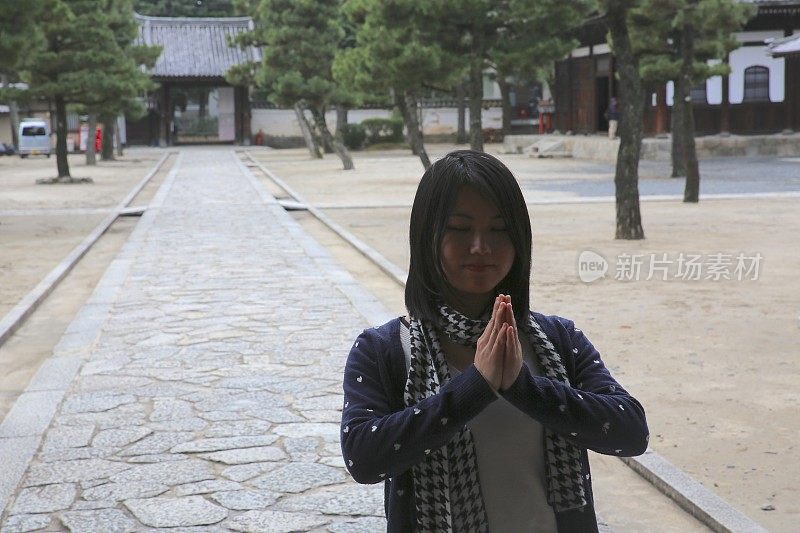 年轻的日本女士在日本寺庙祈祷