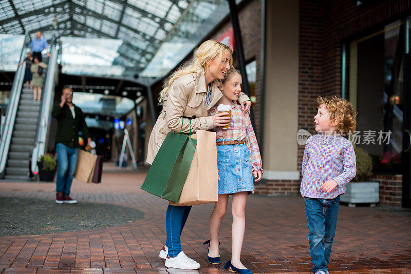 一位年轻的母亲在购物中心和她的孩子们聊天