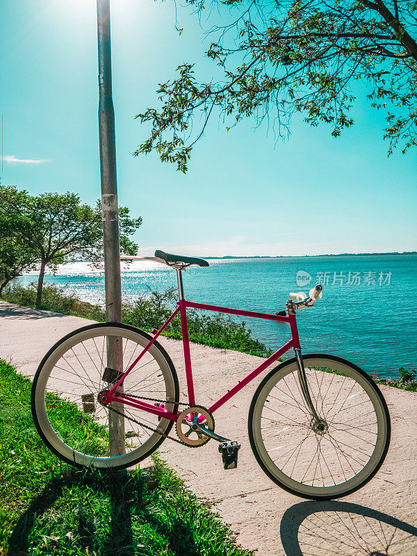 固定齿轮自行车没有刹车在凉爽的日落滨水边缘。怀旧复古的风格。城市在背景中，河流平静