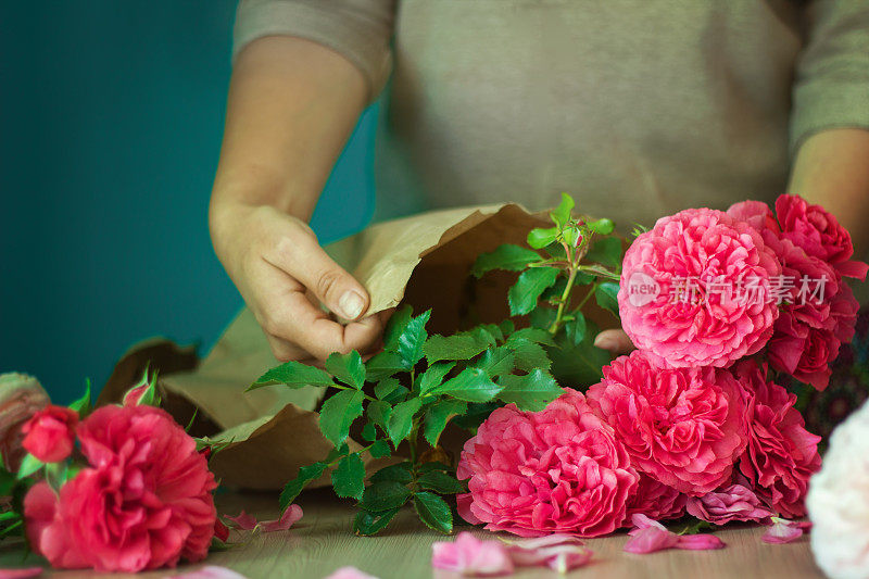 卖花的女孩用纸把漂亮的粉红色玫瑰包起来