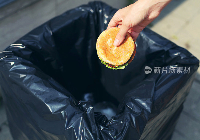 快餐和不健康的饮食概念-手扔一个汉堡在街上的垃圾桶