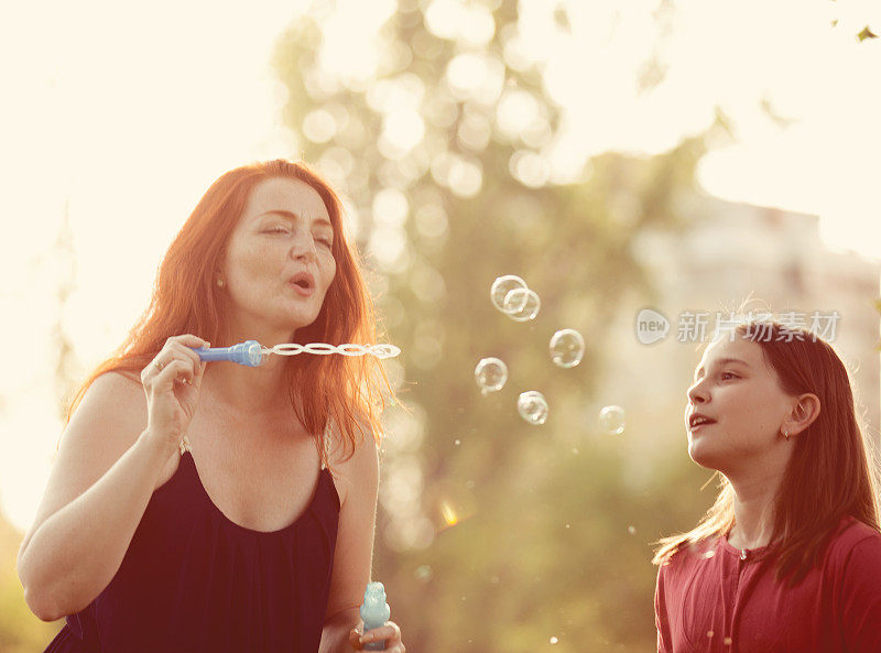 妈妈和女儿在公园吹肥皂泡