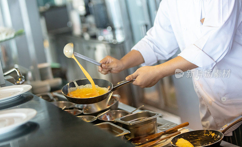 厨师在煎锅里倒煎蛋卷的腹部