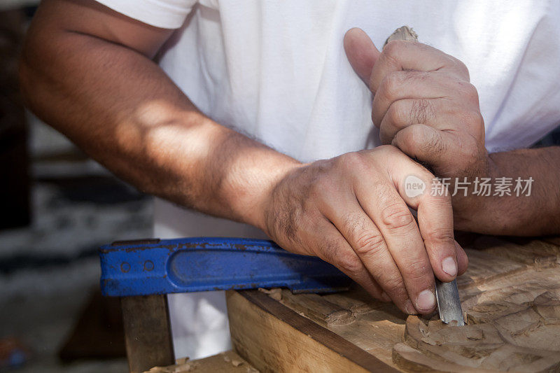 工匠手里拿着凿子，雕刻着一块木头。