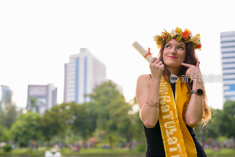 年轻美丽的女子庆祝毕业的肖像在泰国曼谷伦皮尼公园