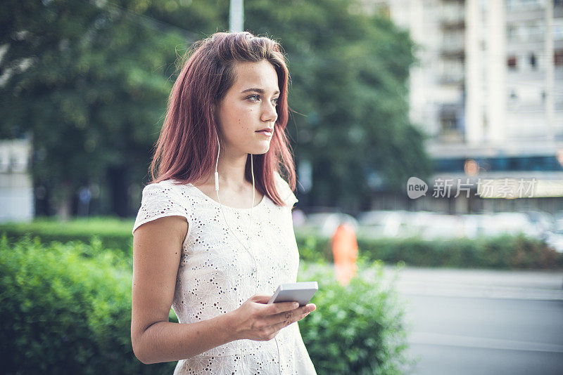 优雅的年轻女子在城里听她的音乐