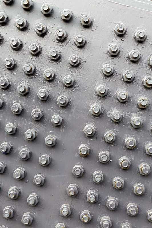 涂漆的金属板上一排排的螺栓和螺母