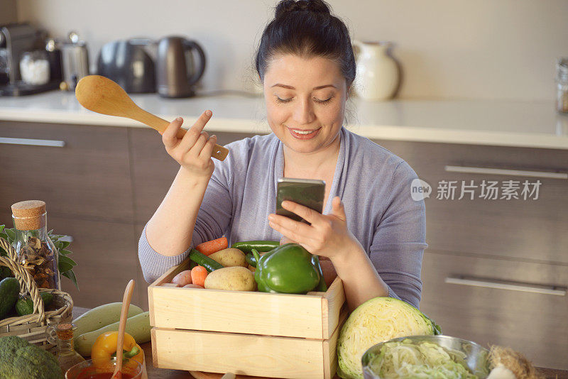 女人在厨房做饭(用智能手机)