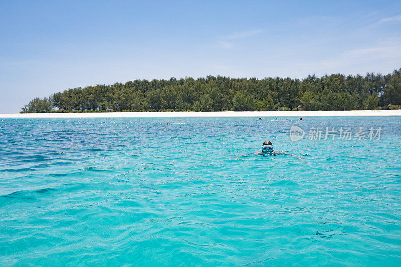 年轻女子浮潜周围的热带岛屿
