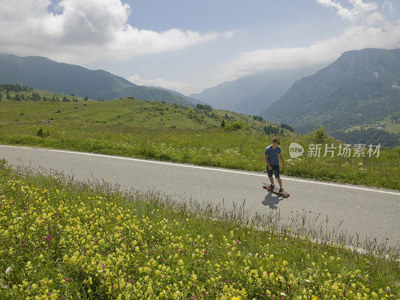 年轻人沿着山路长板而下