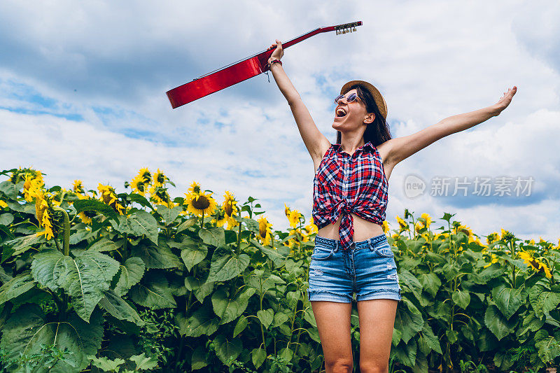 在向日葵地里拿着吉他的女人