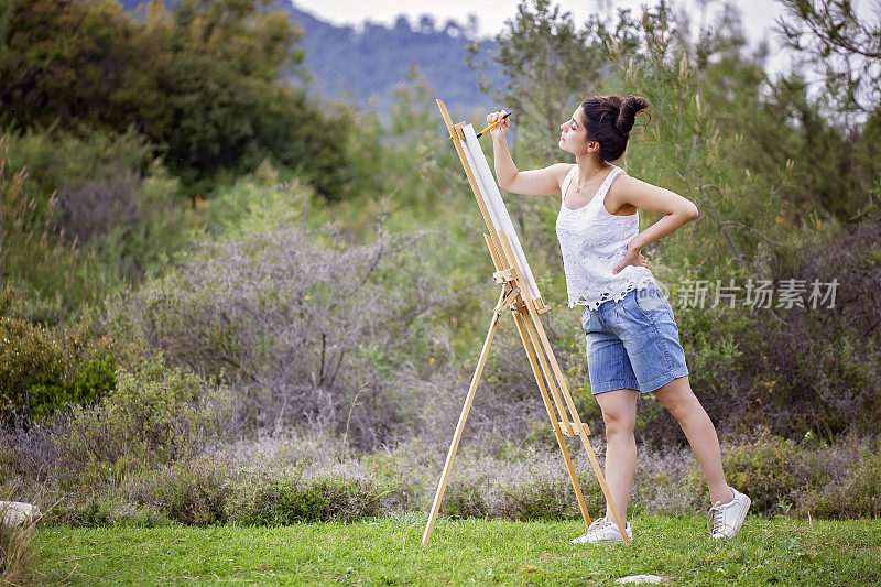 才华横溢的年轻艺术家在户外画风景画。