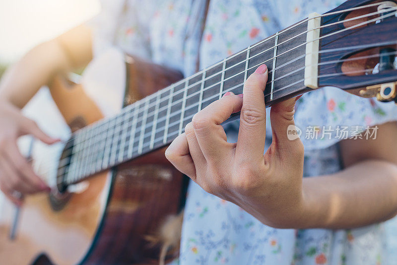 特写，年轻的女音乐家在户外弹奏原声吉他