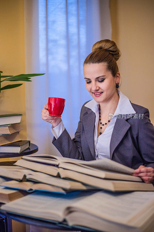 疲惫的女人一边工作一边喝茶