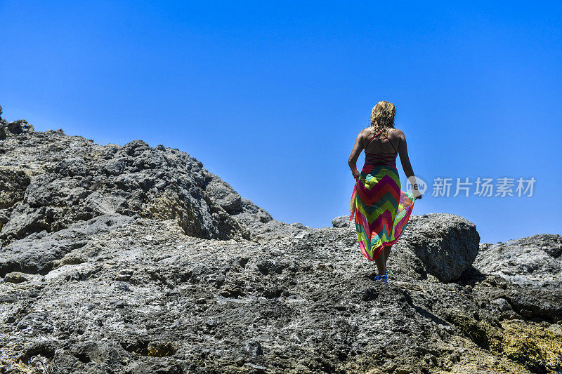 在岩石顶端的女人望着大海。