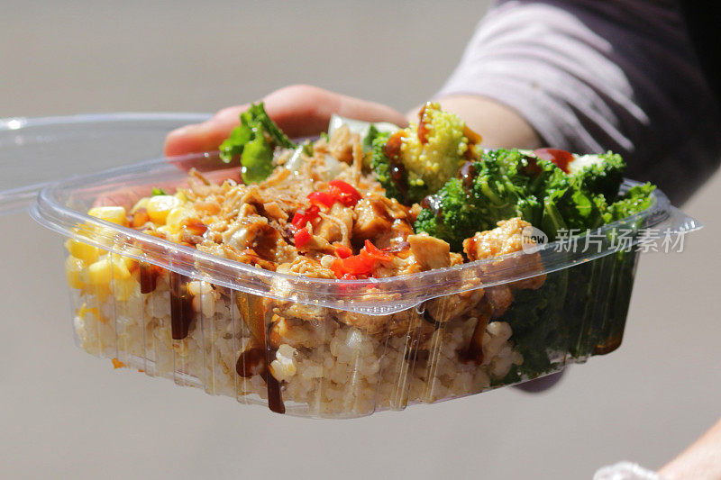 在户外烧烤街的食品市场上健康地吃什锦米饭沙拉，食物被装在塑料盒里，冷白米饭，甜玉米，鸡肉炒洋葱，辣椒，花椰菜，随时可以拿在手里吃