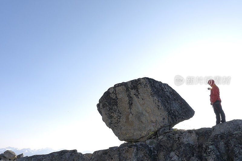 登山者拿着相机站在悬崖顶上