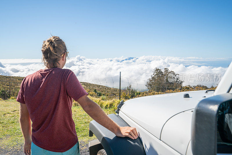 坐在车旁的年轻人在云上凝望夕阳