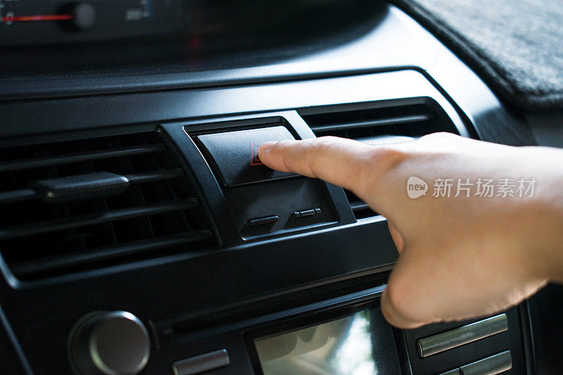 特写，手指触摸汽车仪表板上的紧急按钮。