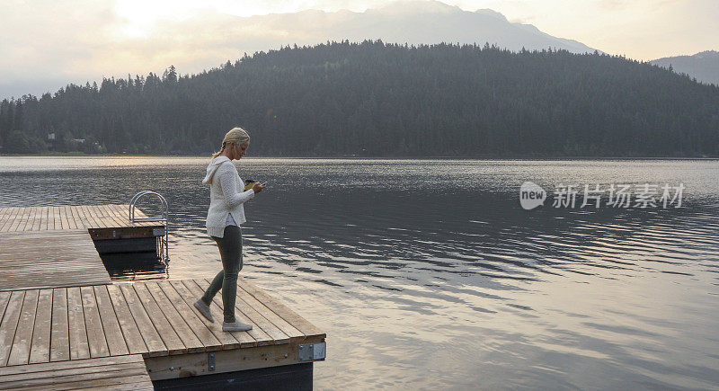 一个成熟的女人停在木码头上，眺望着湖面