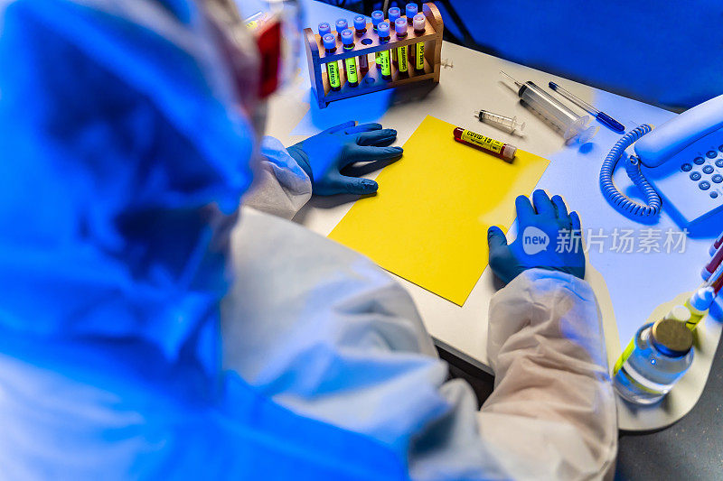 实验室科学家坐在桌子上拿着血液样本病毒试管