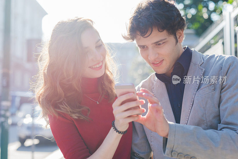 年轻美丽的夫妇用智能手机相爱