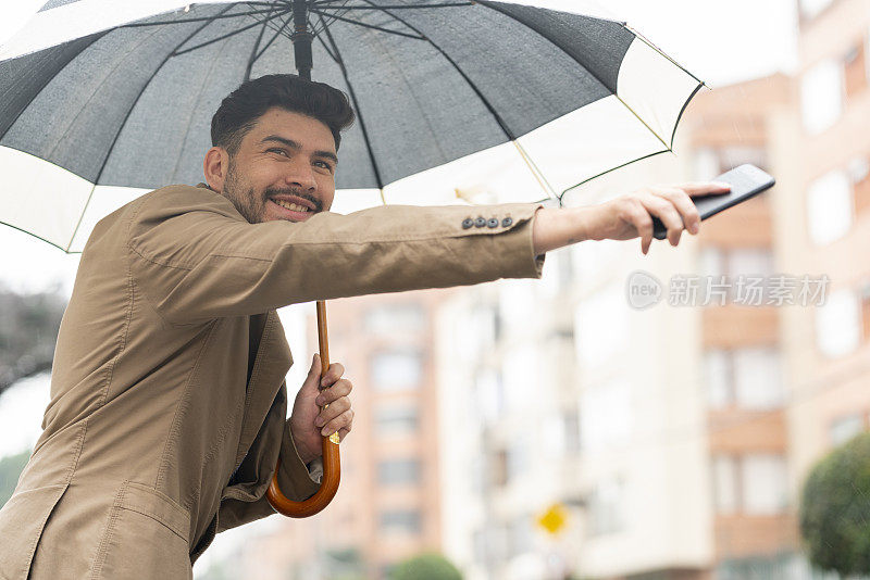 一名年轻人在下雨的时候在街上等待他的优步