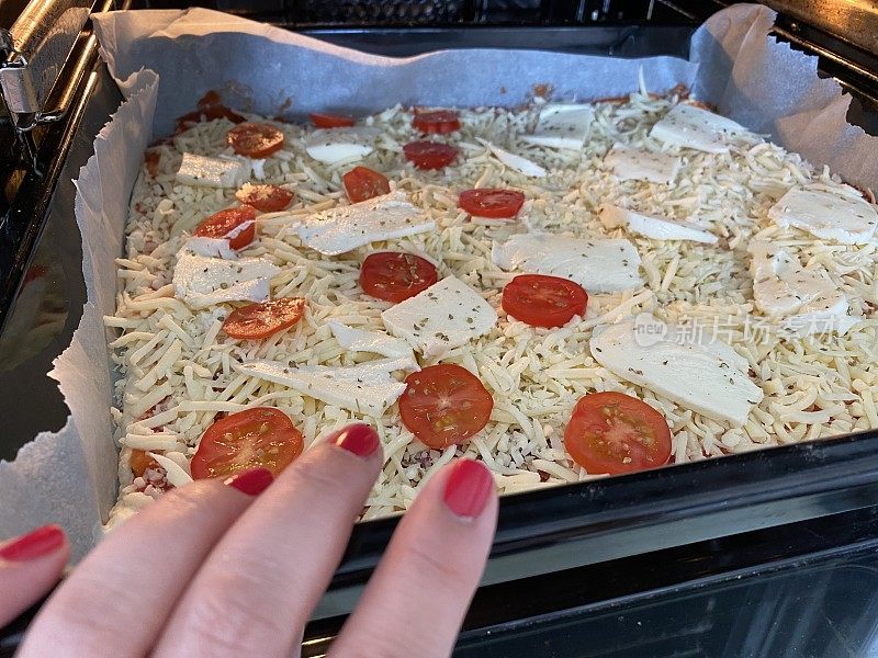 近距离的手把一个新鲜准备的披萨在烤箱烘烤