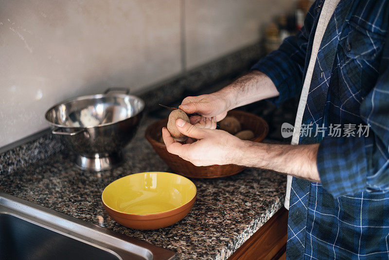 隔离烹饪:一名男子在煮土豆之前剥土豆皮