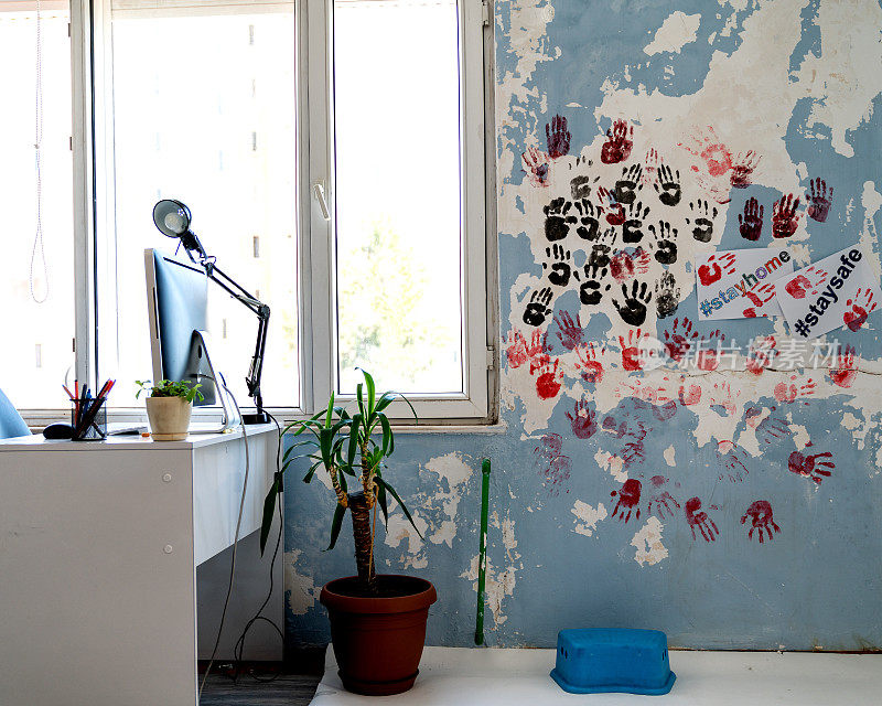 客厅墙上的彩色手指画上写着“待在家里，注意安全”