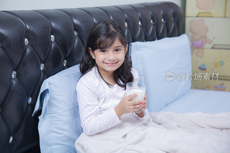 小女孩拿着一杯牛奶在卧室库存照片