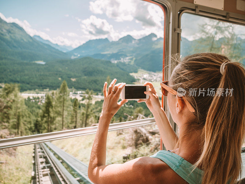 游客在缆车上用手机拍摄美丽的山景