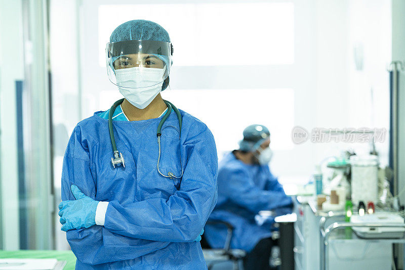 在ICU医院，医生交叉双臂看着镜头，穿着生物安全服