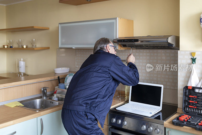 一位高级工人正在修理厨房里的排气过滤器。