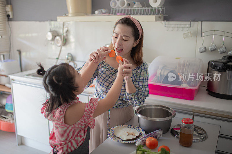 亚洲华人母亲准备食物在厨房柜台与她的女儿