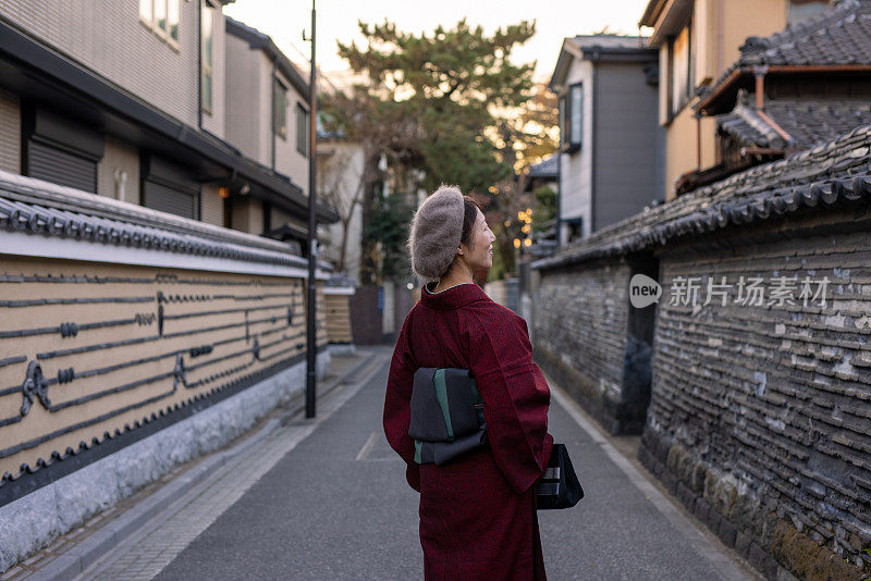 后视图的日本妇女在和服站在狭窄的街道中央