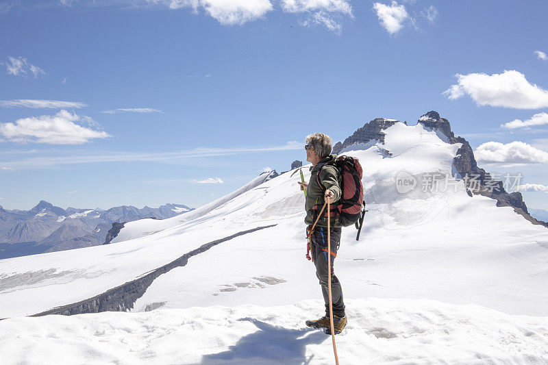 一位男性登山运动员到达了雪山的顶峰