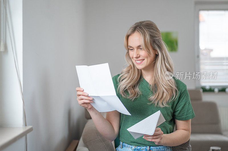 年轻女子微笑着在家里读一封信