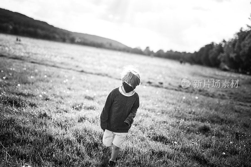 8岁男孩在草地上奔跑，戴着防护面具，黑白相间
