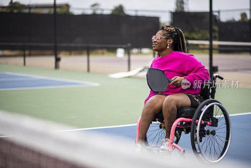 年轻的黑人残疾妇女在轮椅上与朋友玩皮球
