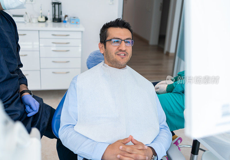牙医正在检查年轻男子的牙齿。牙科医生检查牙科x光片。男牙医向病人讲解牙齿x光片
