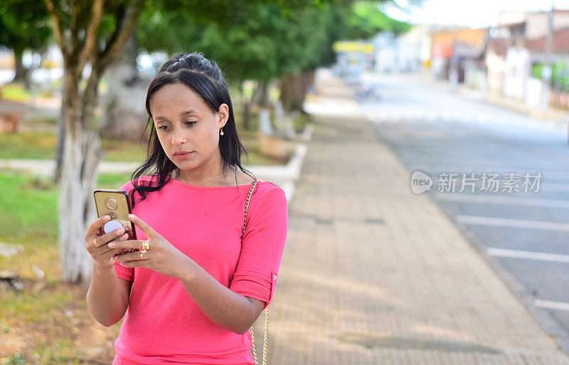 一个年轻女子在街上用手机搜索信息