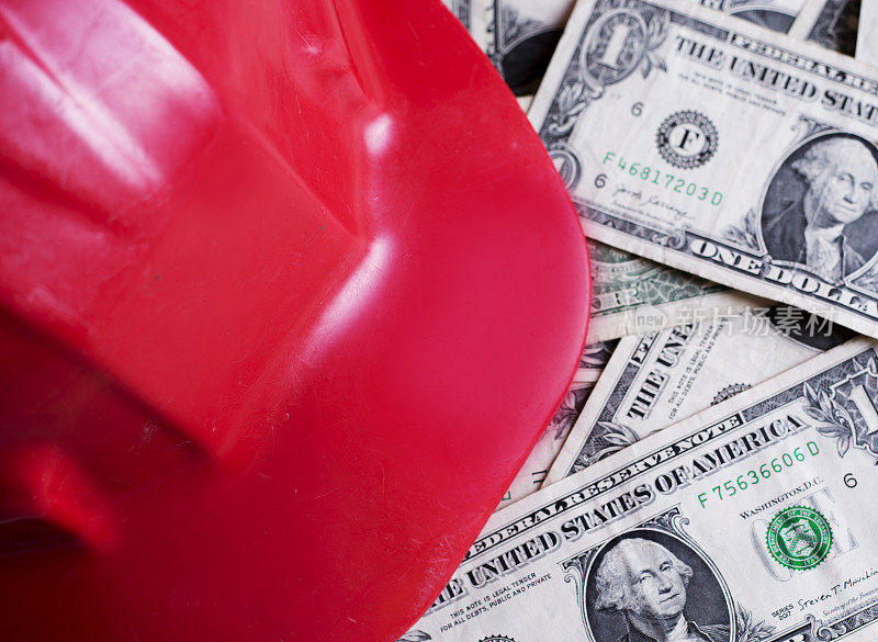 红色建筑安全帽的背景是一美元的钞票。