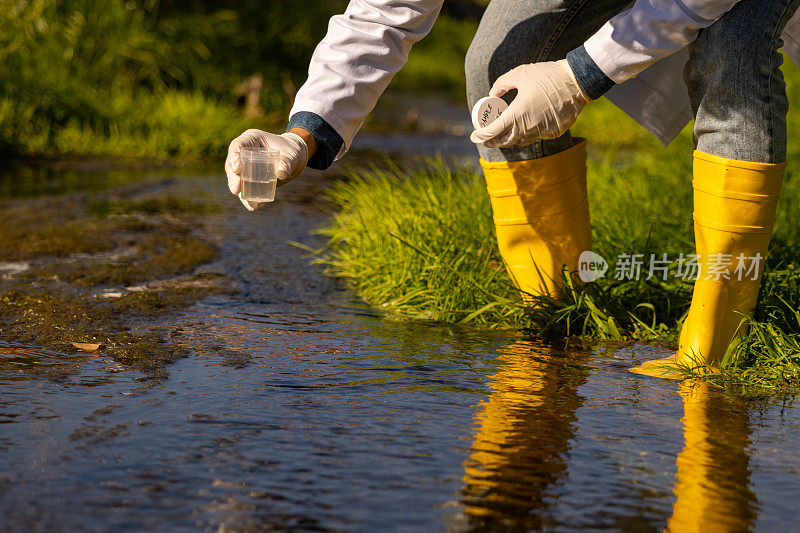 无法辨认的微生物学家，用样本瓶从城市河流中取样分析