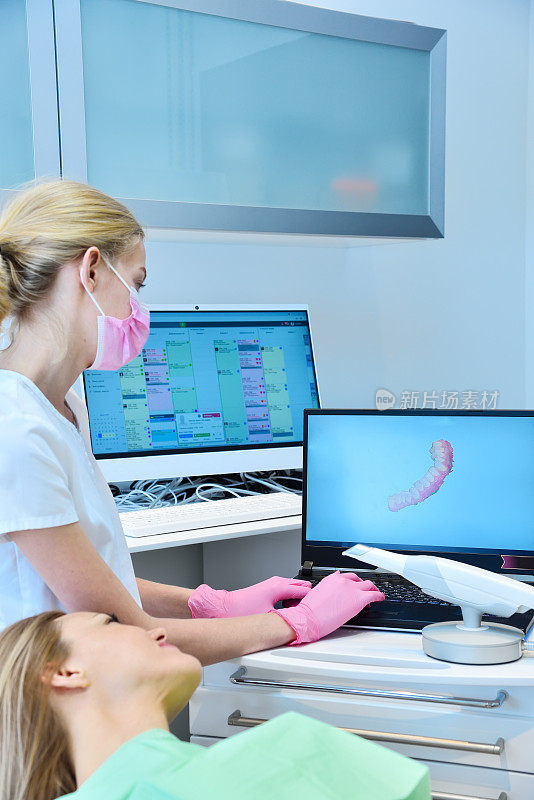 女牙医和病人在笔记本电脑屏幕上观看牙科3d扫描