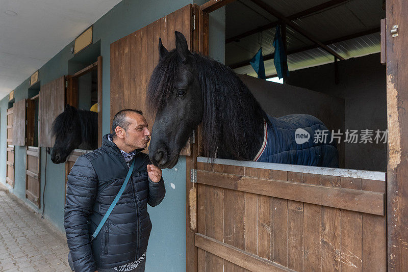 驯马师在马厩里亲吻一匹纯种马