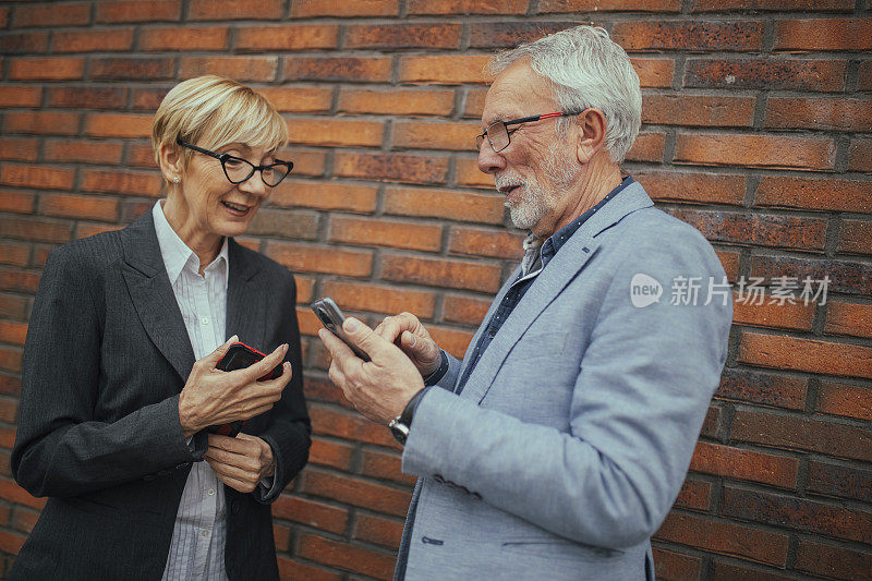 一位头发花白的工程师和一位同事站在城市供热厂前，给她看他手机上的东西。
