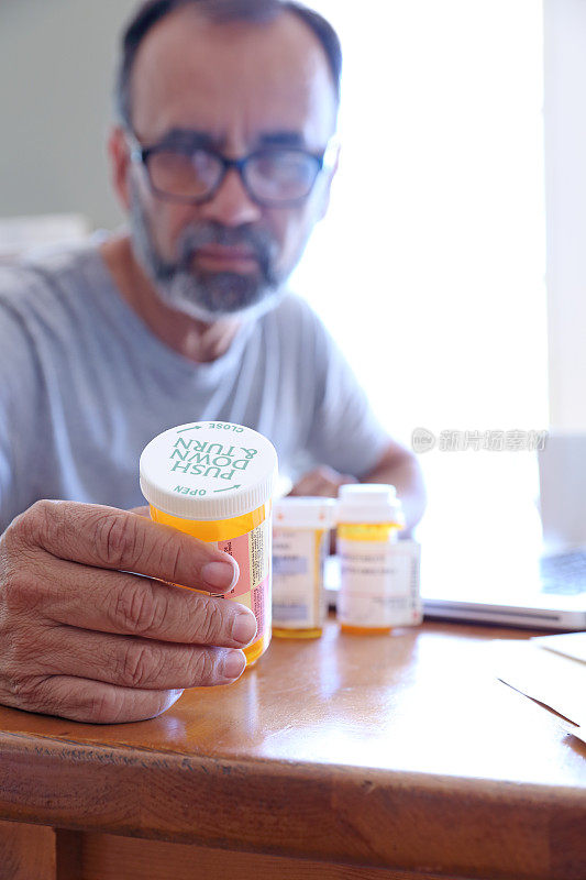 西班牙裔男子坐在餐桌旁阅读药物标签