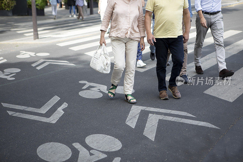 行人和骑自行车的人走过十字路口的脚的特写