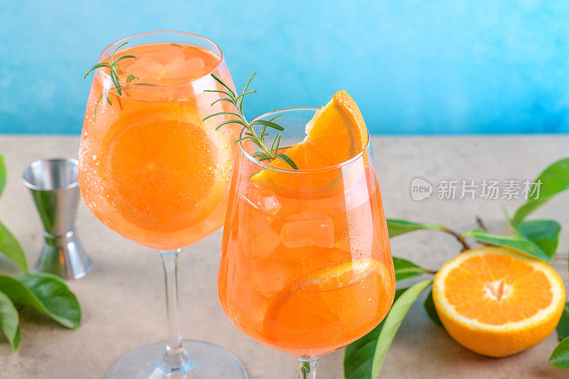 经典的意大利开胃酒，两杯加冰，蓝色背景的橙色，大理石平台